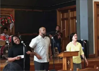  ?? JULIE ZAUZMER, WASHINGTON POST ?? Brittany Wells, left, Pastor Emmett Price and Hilary Davis lead a hymn at Community of Love Christian Fellowship in Boston.