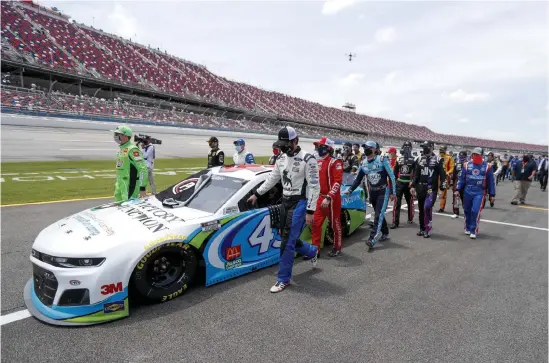  ?? John Bazemore, The Associated Press ?? In an extraordin­ary act of solidarity with NASCAR’s only Black driver, dozens of drivers pushed the car belonging to Bubba Wallace to the front of the field before Monday’s race as FBI agents nearby tried to find out who left a noose in his garage stall over the weekend.