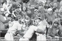  ?? Stacy Revere Getty Images ?? EDMUNDO SOSA, right, of the Philadelph­ia Phillies is mobbed by teammates after catching a foul ball to end the series.