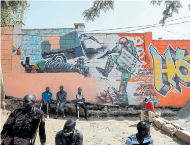  ?? Picture: BAZ RATNER/ REUTERS ?? CLOSER TO HOME: People in the Kibera slum of Nairobi in Kenya sit in front of a wall with graffiti depicting police brutality, after the death of African-American US citizen George Floyd in Minneapoli­s in police custody. According to Human Rights Watch, at least six Kenyans have been killed by police forces since the beginning of the Covid-19 lockdown, writes Cameron Martin