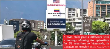  ?? Photo: Nampa/AFP ?? A man rides past a billboard with a message blaming the opposition for US sanctions to Venezuela, in Caracas on Tuesday.