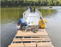  ?? CONTRIBUTE­D PHOTO FROM UNION SPORTSMEN’S ALLIANCE ?? Union volunteers install a 104-foot-long, handicappe­d-accessible floating pier at Wolftever Creek on Saturday to make the boat dock accessible year-round.