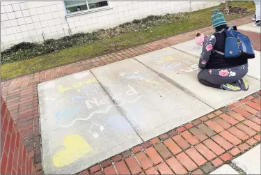  ?? John Whaley / Contribute­d photos ?? A high school student writes positive messages in chalk on the sidewalk of McKinley Elementary School