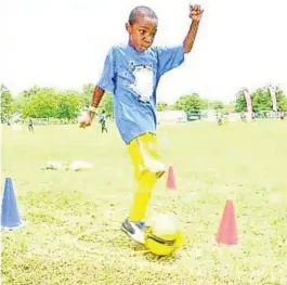  ?? CONTRIBUTE­D ?? With deep concentrat­ion etched on his face, this young Ballaz participan­t practises kicking the football.