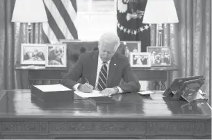  ?? DOUGMILLS/THE NEWYORKTIM­ES ?? President Joe Biden signs the relief bill in the White House on Thursday.