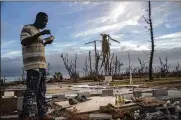  ?? RAMON ESPINOSA / AP ?? Jeffrey Roberts eats while searching through the rubble of his relatives’ home destroyed by Hurricane Dorian in Grand Bahama, Bahamas. The death toll stands at 50 and the missing at an alarming 1,300 people.