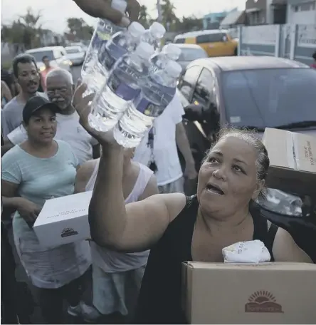  ??  ?? Survivors receive food and water from volunteers and municipal police in the aftermath of Hurricane Maria