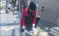  ??  ?? Gregg Donovan, who goes by The Ambassador, places flowers on the Hollywood Walk of Fame star of director Richard Donner on Tuesday.