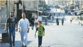  ?? (Reuters) ?? PEOPLE ARE SHOWN walking along a street in Deir al-Zor, Syria, in this handout picture provided by the official Syrian news agency SANA on Monday.