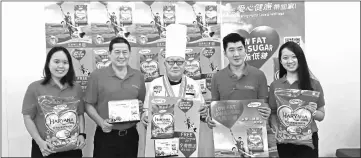  ??  ?? Lim (second left) and Chef Goh join Liansin Trading staff members to promote the limited-edition 2017 table calendar and also the poster version.