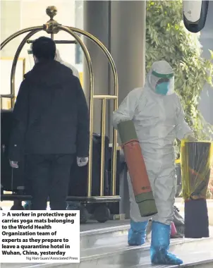  ?? Ng Han Guan/Associated Press ?? A worker in protective gear carries yoga mats belonging to the World Health Organizati­on team of experts as they prepare to leave a quarantine hotel in Wuhan, China, yesterday