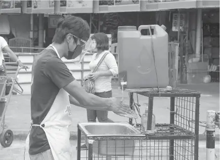  ?? Photo by Jean Nicole Cortes ?? SIMPLE AND EFFECTIVE. A man washes his hands at the Baguio City Public Market. Experts continue to remind the public, proper hand washing is the best way to become Covid-19 free.