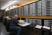  ?? (AP/Lincoln Journal Star/Kenneth Ferriera) ?? Vaughn Gebers organizes voter registrati­on cards while seated in front of stacked ballot boxes at the Lancaster County Election Commission on Tuesday in Lincoln, Neb.