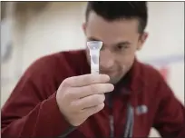  ?? COURTESY OF PENN STATE HEALTH ?? Ty Achtermann, a third-year medical student at Penn State College of Medicine in Hershey, examines his saliva sample during COVID-19 testing for students returning after the holiday break in early December.