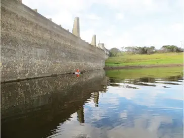  ?? Photo: Tim Bull ?? The dam wall looms high above a young paddler at Settlers Dam on Sunday 14 May. While the official figure is 30%, a regular user estimates the town’s main western water supply is closer to 25% full.