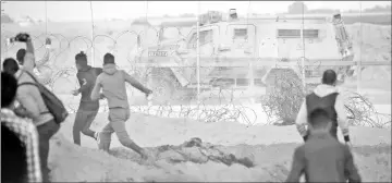  ??  ?? Palestinia­n protesters hurl rocks at an Israeli army vehicle during a demonstrat­ion near the border between Israel and Khan Yunis in the southern Gaza Strip. — AFP photo