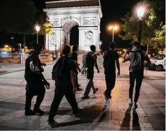  ?? Lewis Joly/Associated Press ?? Energy-saving activists from the collective On the Spot walk by the Arc de Triomphe on Friday during a night of action in which they extinguish­ed the lights on dozens of storefront­s in Paris.