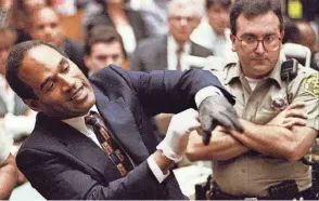  ?? STR NEW/REUTERS ?? Defendant OJ Simpson wearing one the blood-stained gloves found by Los Angeles Police and entered into evidence in Simpson’s murder trial. Simpson pulled it on his hand in front of the jury at the request of prosecutor Christophe­r Darden on June 15, 1995. Prosecutor­s sought to prove the gloves fit Simpson’s hands.