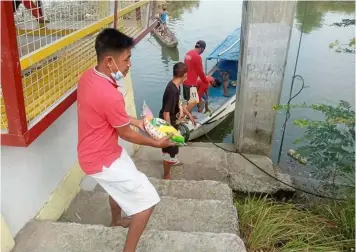  ?? AID TO BOATMEN. (Contribute­d photo) ?? Boatmen in Masantol town receive rice assistance from the local government headed by Mayor Danilo Guintu.