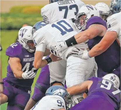  ??  ?? Northweste­rn defenders Tyler Lancaster ( right) and Paddy Fisher stop QB Griffin Dahn on fourth down. | JONATHAN DANIEL/ GETTY IMAGES