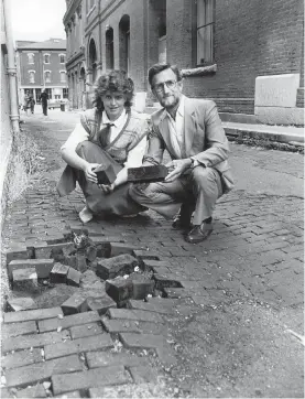  ??  ?? Sept. 12, 1985: Don Wells, then president of the Hallmark Society, and Melissa McLean, who was with Tourism Victoria, examine the state of the wooden blocks of Waddington Alley at a time when the city engineer wanted to replace them with asphalt.