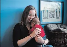  ?? CHRISTOPHE­R KATSAROV CANADIAN PRESS FILE PHOTO ?? A Toronto mother holds her two-month-old son in her apartment. A new report tracking child poverty rates across all 338 federal riding shows that four in every 10 children Toronto Centre live in poverty.