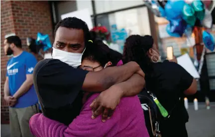  ?? Associated Press file photo ?? ■ Demonte Munerlyn, son of Calvin Munerlyn, holds his aunt Sharion Munerlyn on May 3 as the two cope with the death of Calvin Munerlyn in Flint, Mich. A woman, her adult son and husband have been charged in the fatal shooting of Calvin Munerlyn, a security guard who refused to let her daughter enter a Family Dollar in Michigan because she wasn't wearing a face mask. Retailers have been posting incidents of attacks occurring around the country. "We are hearing an increasing number of reports of abuse and violence directed against retail workers who are doing their jobs by asking customers to wear face masks or comply with other guidelines intended to protect their own safety," David French, senior vice president for government relations for the National Retail Federation, said in a statement.