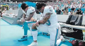  ?? WILFREDO LEE THE ASSOCIATED PRESS ?? Dolphins Kenny Stills, left, and Albert Wilson kneel during the playing of the U.S. national anthem before a game against the Tennessee Titans on Sunday in Miami Gardens, Fla.