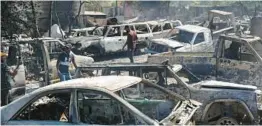  ?? ODELYN JOSEPH/AP ?? People look for salvageabl­e pieces from burned cars at a mechanic shop that was set on fire during violence by armed gangs in Port-au-Prince, Haiti, on March 25.