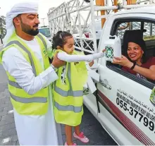  ??  ?? Above: Five-year-old Meera Nasser joins her father, Dubai Police officer Nasser Eid, in distributi­ng iftar packs to motorists near City Walk in Dubai.