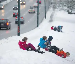  ?? GERRY KAHRMANN/PNG ?? Children take to the hill at Hastings Community Park in Vancouver on Wednesday as drivers commute along East Hastings.