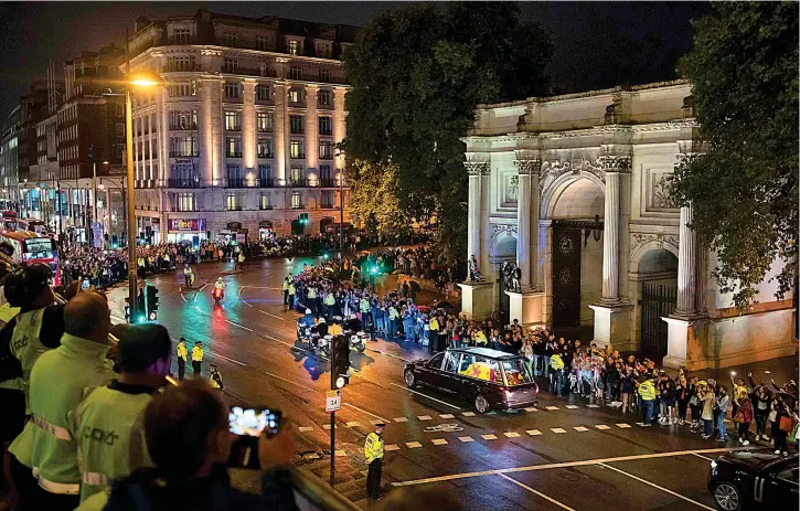  ?? ?? Respect: Workmen in hi-vis jackets downed tools at Marble Arch to join the masses lining the streets filming the historic passage to the Palace