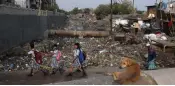  ?? — AFP ?? Schoolgirl­s walk past a sewage drain canal full of garbage in Taimur Nagar slum area in New Delhi.