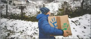  ??  ?? A boy carries a box containing basic food, hygiene and medical products. (AP/Andreea Alexandru)