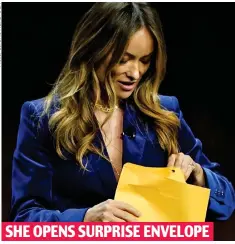  ?? ?? SHE OPENS SURPRISE ENVELOPE
Olivia Wilde with the package handed to her on stage