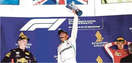  ?? AFP PIC ?? Mercedes AMG Petronas’ Lewis Hamilton (centre) celebrates winning the Singapore GP as second placed Red Bull’s Max Verstappen (left) and third placed Ferrari’s Sebastian Vettel look on yesterday.