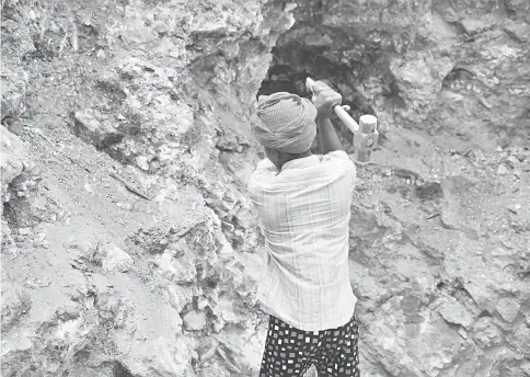  ??  ?? Babloo, 16, uses a hammer to break away pieces of mica in Giridih district in the eastern state of Jharkhand. — Reuters photos