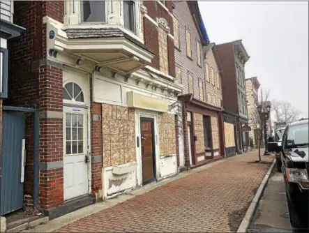  ?? NICHOLAS BUONANNO — NBUONANNO@TROYRECORD.COM ?? Boards cover the windows of several businesses and buildings on Remsen Street in Cohoes damaged by Thursday’s devastatin­g downtown fire.