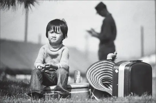  ?? Photograph­s by Don Bartletti ?? A SUITCASE DOES double duty for a boy waiting as his family is processed. Almost overnight, refugee camps had sprung up across the U.S. for 100,000-plus Vietnamese.