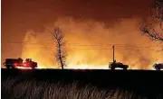  ?? [PHOTO BY BO RADER, THE WICHITA EAGLE] ?? Firefighte­rs from Kansas and Oklahoma battle a wildfire on March 6 near Protection, Kan. Four large wildfires blazed across almost 800,000 acres of the Texas Panhandle, Kansas and Oklahoma earlier this month, killing two people, thousands of livestock...