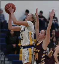  ?? ?? Bloomfield Hills Marian’s Mckenzie Swanson (left) lays up two of her 31 points as Farmington Hills Mercy’s Emily Walker (24) defends during the game played on Friday at Marian High School. The Marlins defeated the Mustangs 70-63.