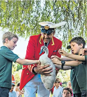  ??  ?? David Barber, the Queen’s Swan Marker, shows a school group a cygnet