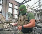  ?? ANDRII MARIENKO/AP ?? A Ukrainian serviceman holds rocket fragments at the ruins of the sports complex of the National Technical University in Kharkiv, Ukraine, on Friday. The building received significan­t damage from a Russian shelling.