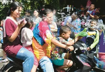  ?? MADAREE TOHLALA/GETTY-AFP ?? Happy New Year: A motorcycli­st is hit with water Saturday in Narathiwat, Thailand, as revelers take part in water fights at a traditiona­l festival ringing in the country’s New Year. Songkran, a three-day shindig that informally extends to a week, is also celebrated under different names in neighborin­g Myanmar, Cambodia and Laos.