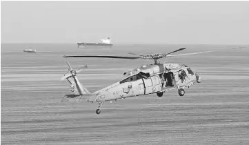  ??  ?? File photo shows a MH-60S helicopter hovering in the air with an oil tanker in the background as the USS John C. Stennis makes its way to the Gulf through the Strait of Hormuz. — Reuters photo