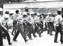  ?? RAY FOSTER/CHICAGO TRIBUNE ?? Police officers duck bottles and stones while advancing on the crowd. Scholars see the unrest as fueled by pent-up anger at exclusion from the mainstream.