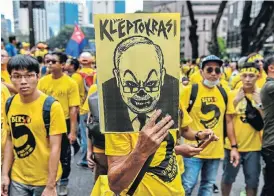  ?? /AFP ?? Economic revolt: Protesters against former Malaysian prime minister Najib Razak, depicted in a poster, call for his resignatio­n at a mass rally in Kuala Lumpur in November 2016. Najib has been charged and arrested for his role in the theft of more than $4bn from the fund he set up.