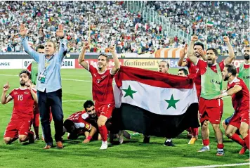  ??  ?? Syria’s draw with Iran put them one match away from playing in the 2018 World Cup; some Assad supporters in the stands, right