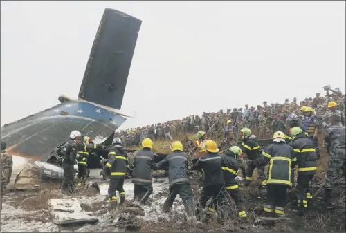  ??  ?? Nepalese firemen at work amid the debris after a passenger plane from Bangladesh crashed at the airport in Kathmandu, Nepal,