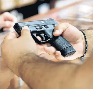  ?? BUXEDA/ORLANDO SENTINEL
RICARDO RAMIREZ ?? A customer looks at a handgun at the Kissimmee location of The Armories on Thursday.